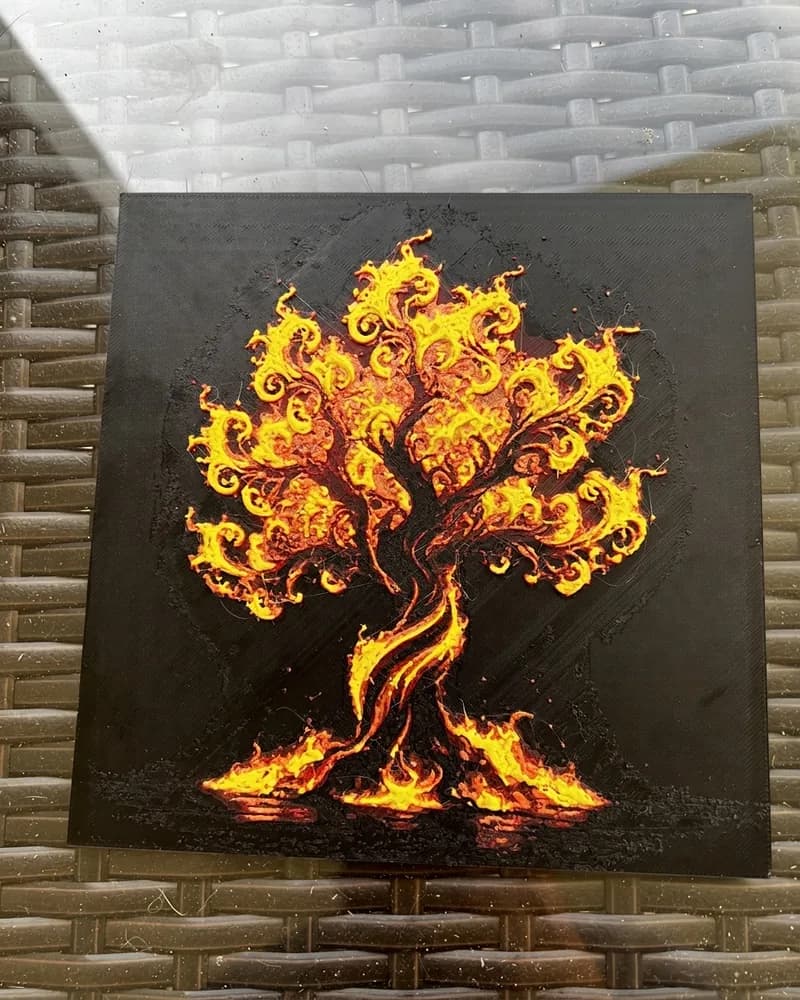 A 3D-printed wall panel of a tree in flames, in orange and yellow on black