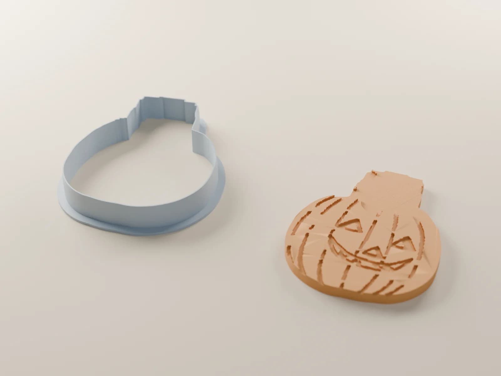 A render of the kitten-and-pumpkin cutter beside the cookie it cuts
