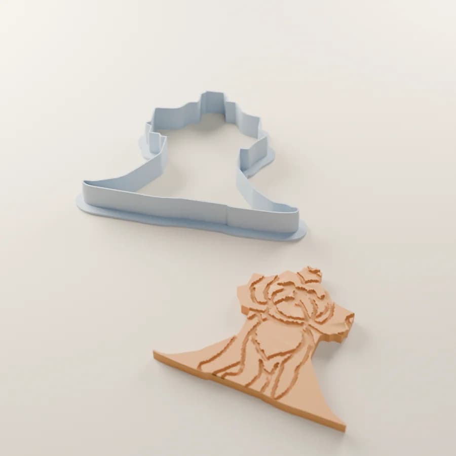 A render of the caped dog’s cutter beside the cookie it cuts